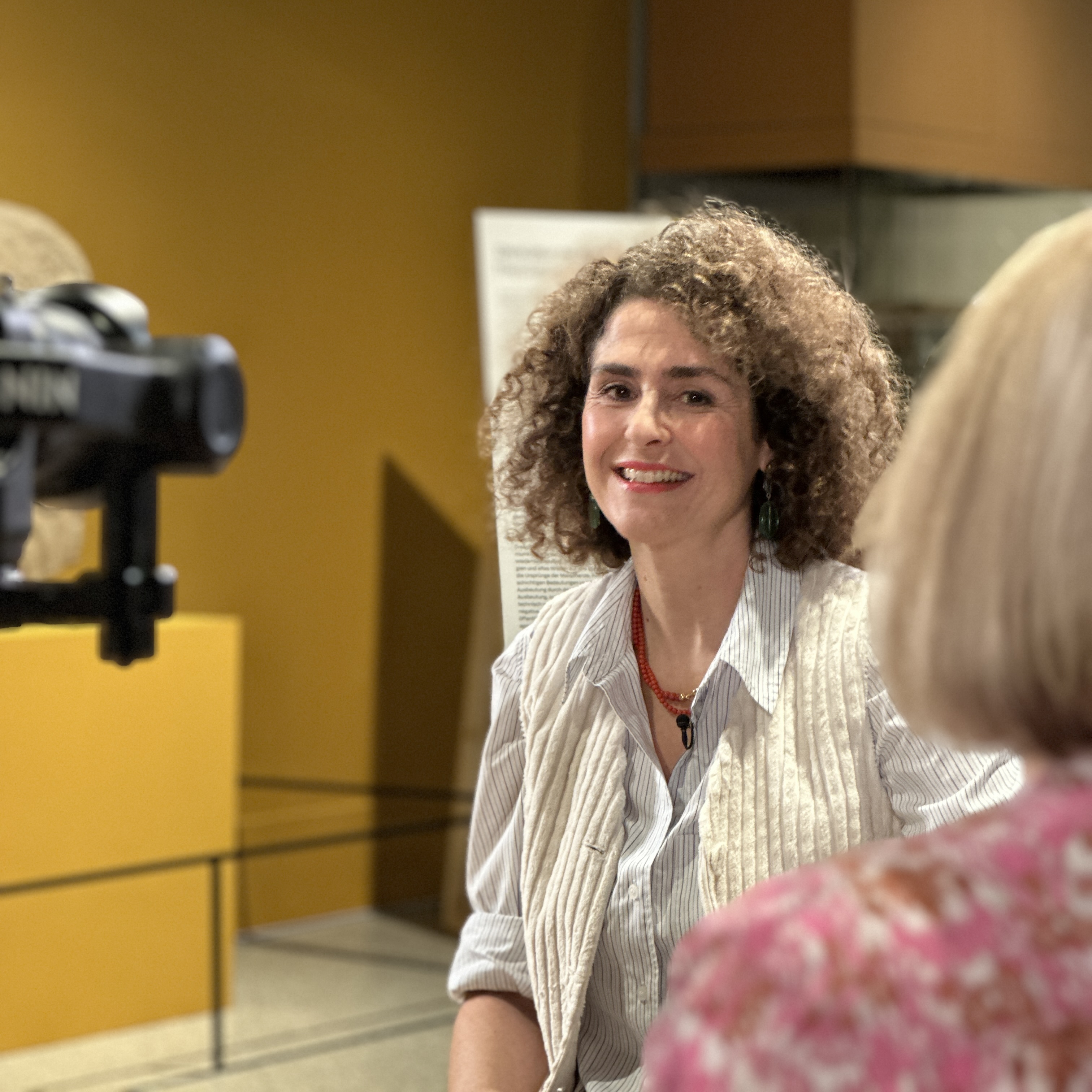 Nora Abu-Oun im Gespräch mit Kuratorin, sie lacht in die Kamera.