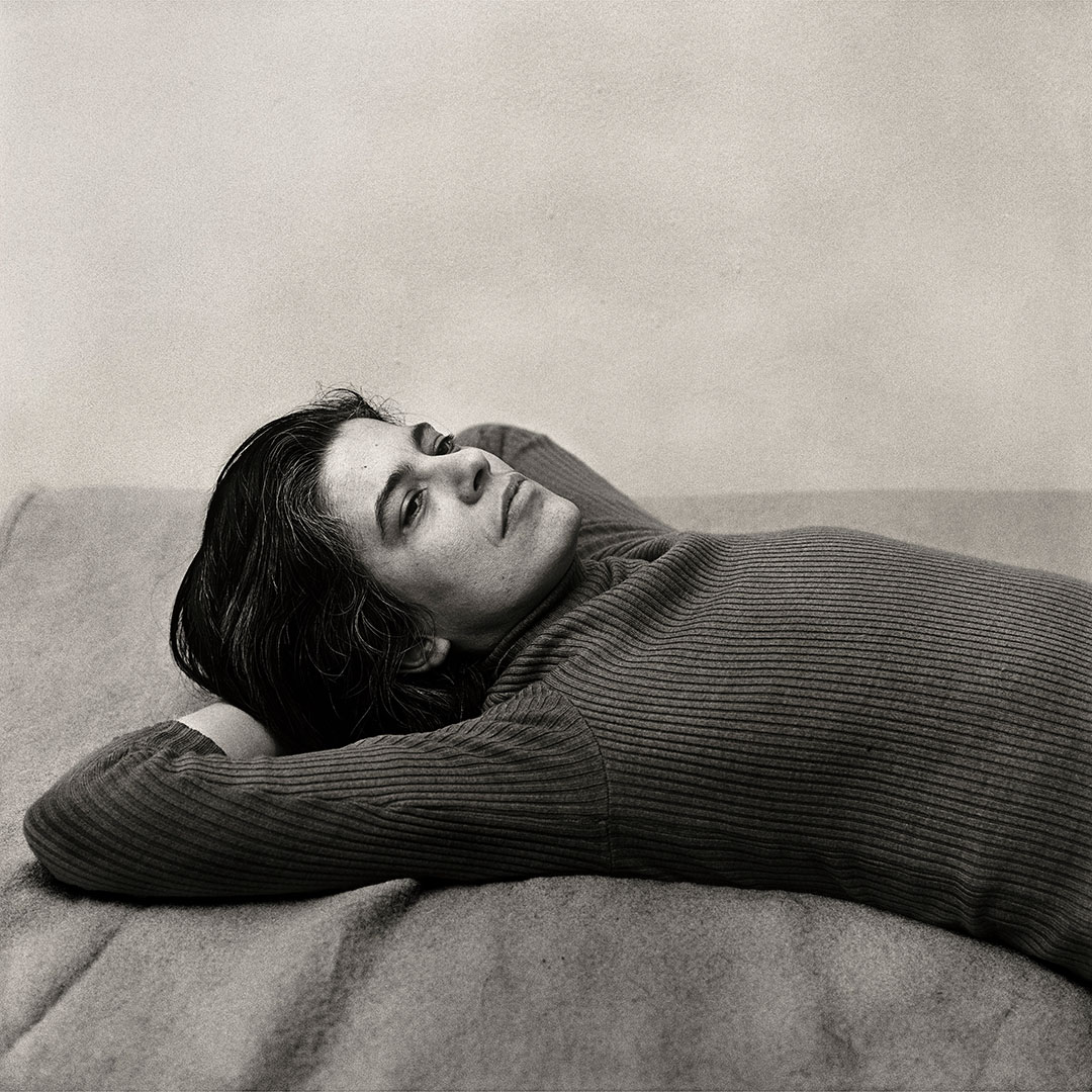 Susan Sontag lies relaxed with her arms behind her head.